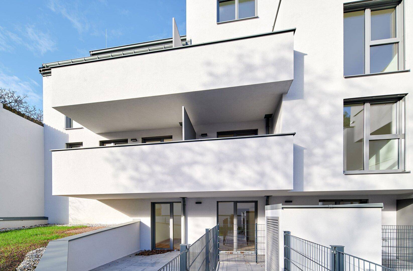 Moderne Wohnanlage mit mehreren Balkonen und Zugang zum Gartenbereich.