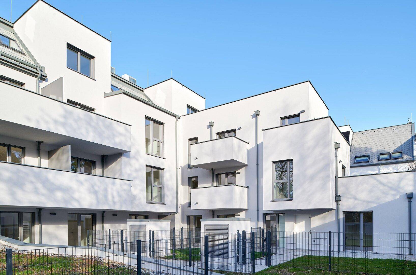 Innenhofansicht eines modernen Wohnkomplexes mit Balkonen und Grünflächen.