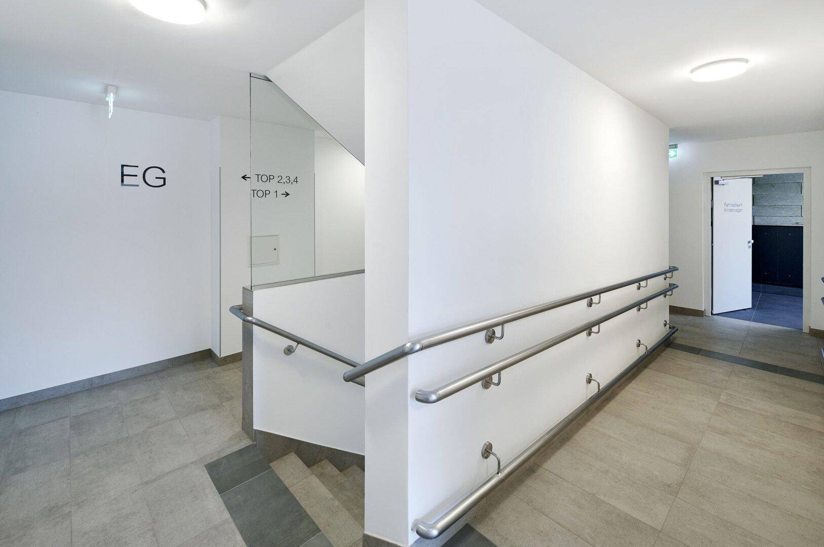 Barrierefreier Eingangsbereich mit Rampe, Handläufen und Fliesenboden im Erdgeschoss.