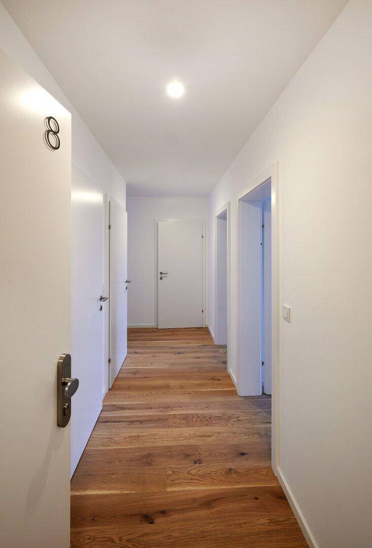 Langer, heller Flur mit Holzboden und mehreren Türen zu den angrenzenden Räumen.