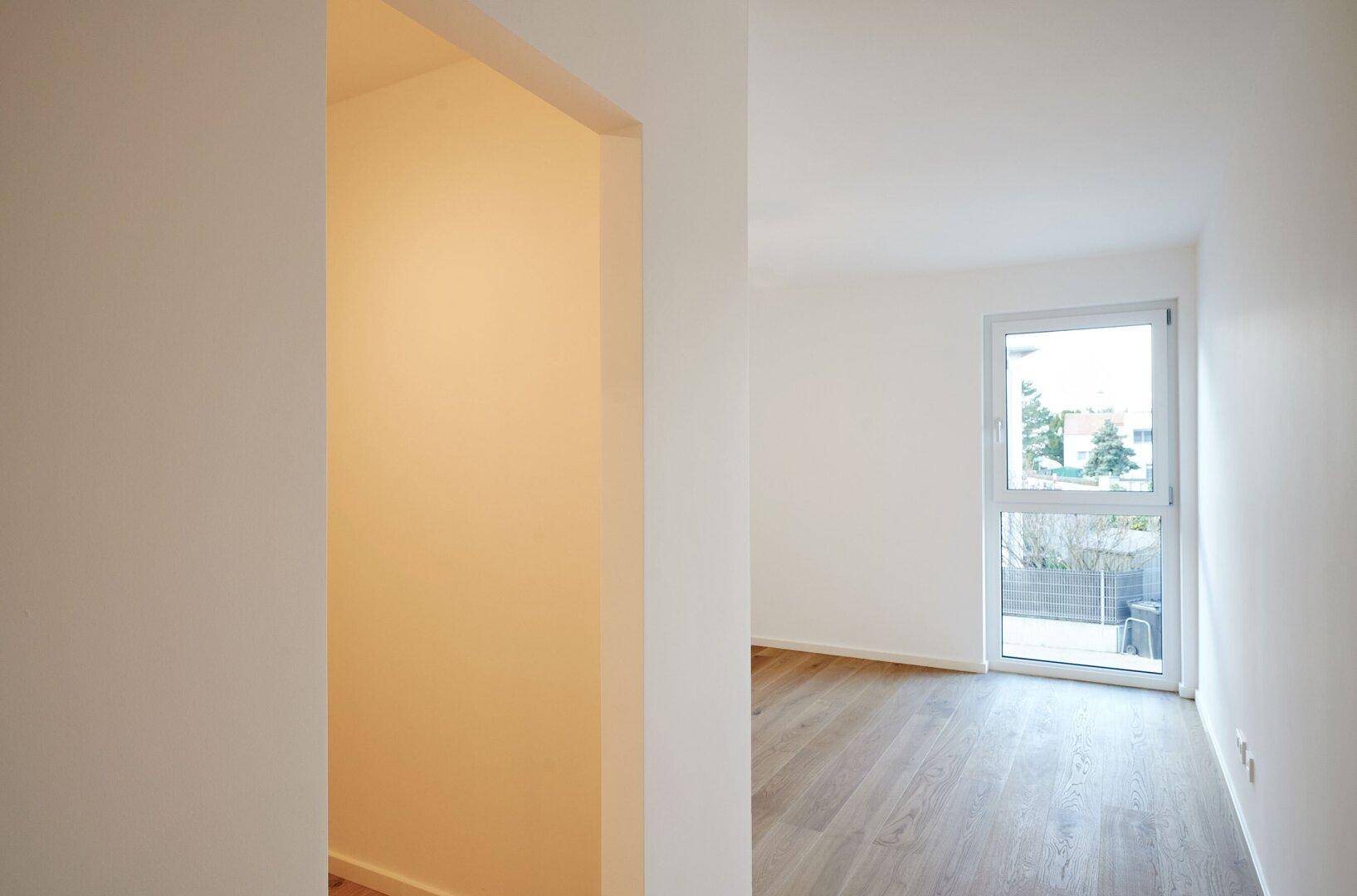 Heller Wohnbereich mit Holzboden und Fenster, das viel Tageslicht hereinlässt.