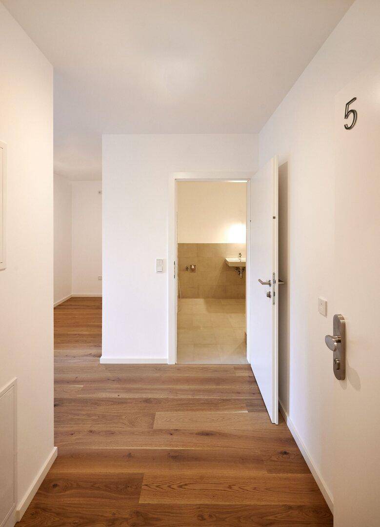 Heller Flur mit Holzboden, der zu den verschiedenen Räumen der Wohnung führt.