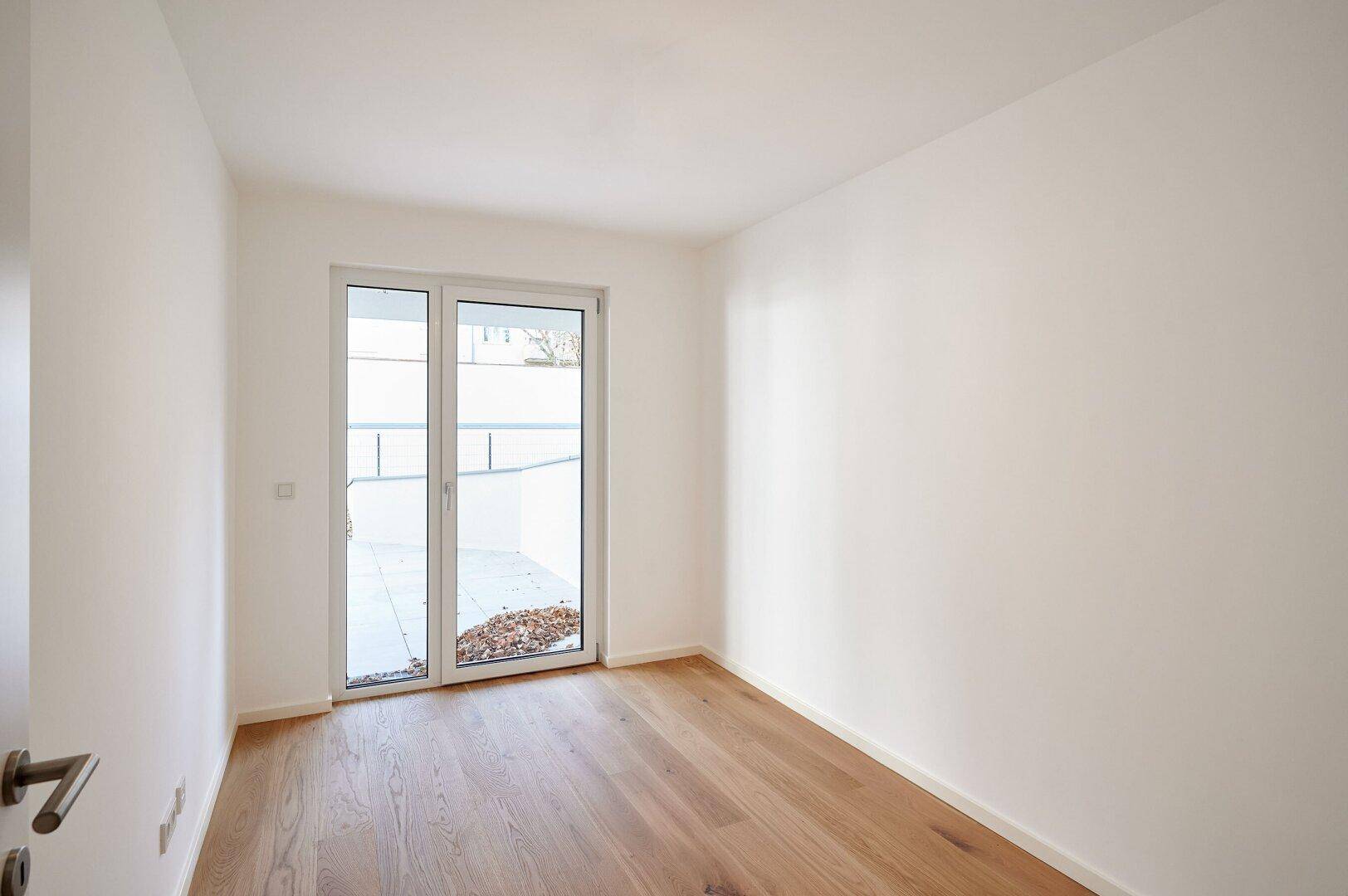 Helles Schlafzimmer mit Holzboden und direktem Zugang zu einem Außenbereich.