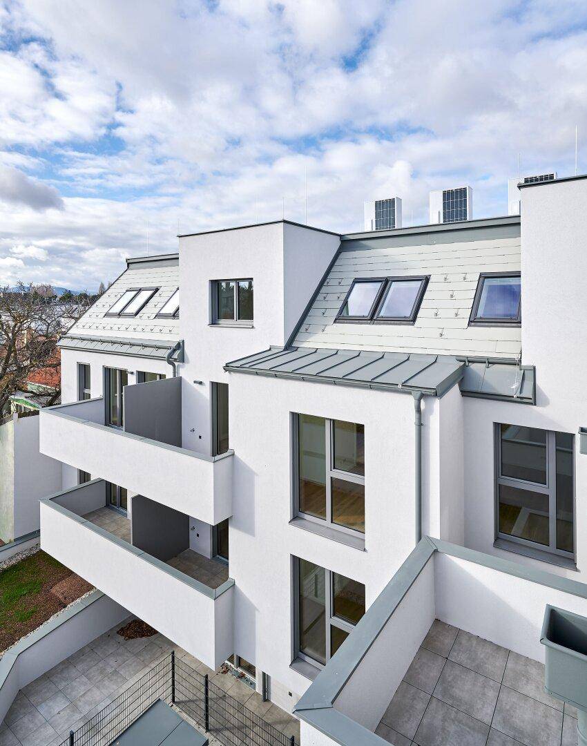 Draufsicht auf die moderne Wohnanlage mit Balkonen, Terrassen und Dachfenstern.