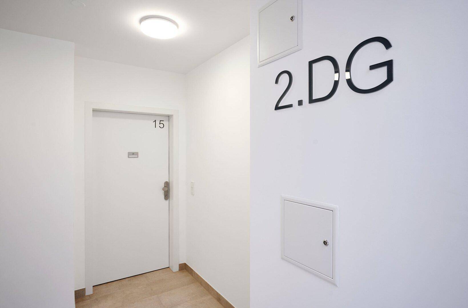 Flur im zweiten Dachgeschoss mit Fliesenboden und Zugang zur Wohnung Nummer 15.