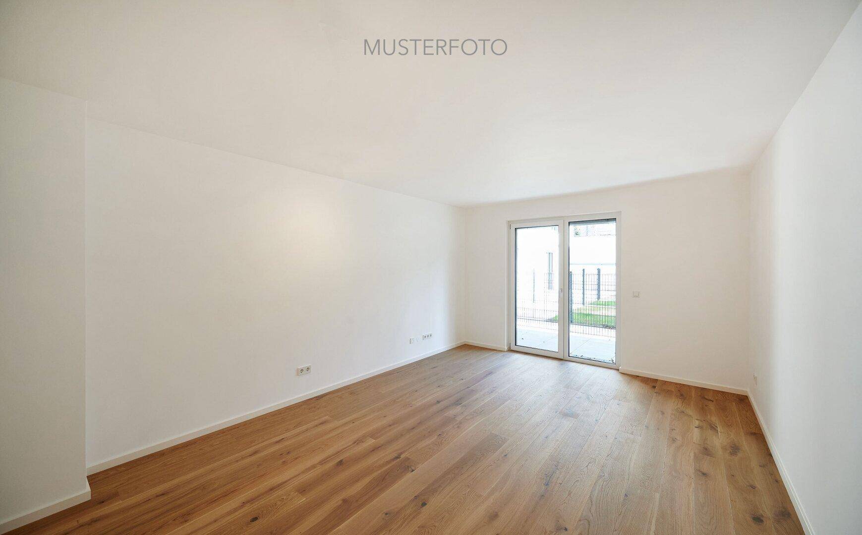 Helles, leeres Wohnzimmer mit Holzboden und Zugang zur Terrasse oder zum Garten.