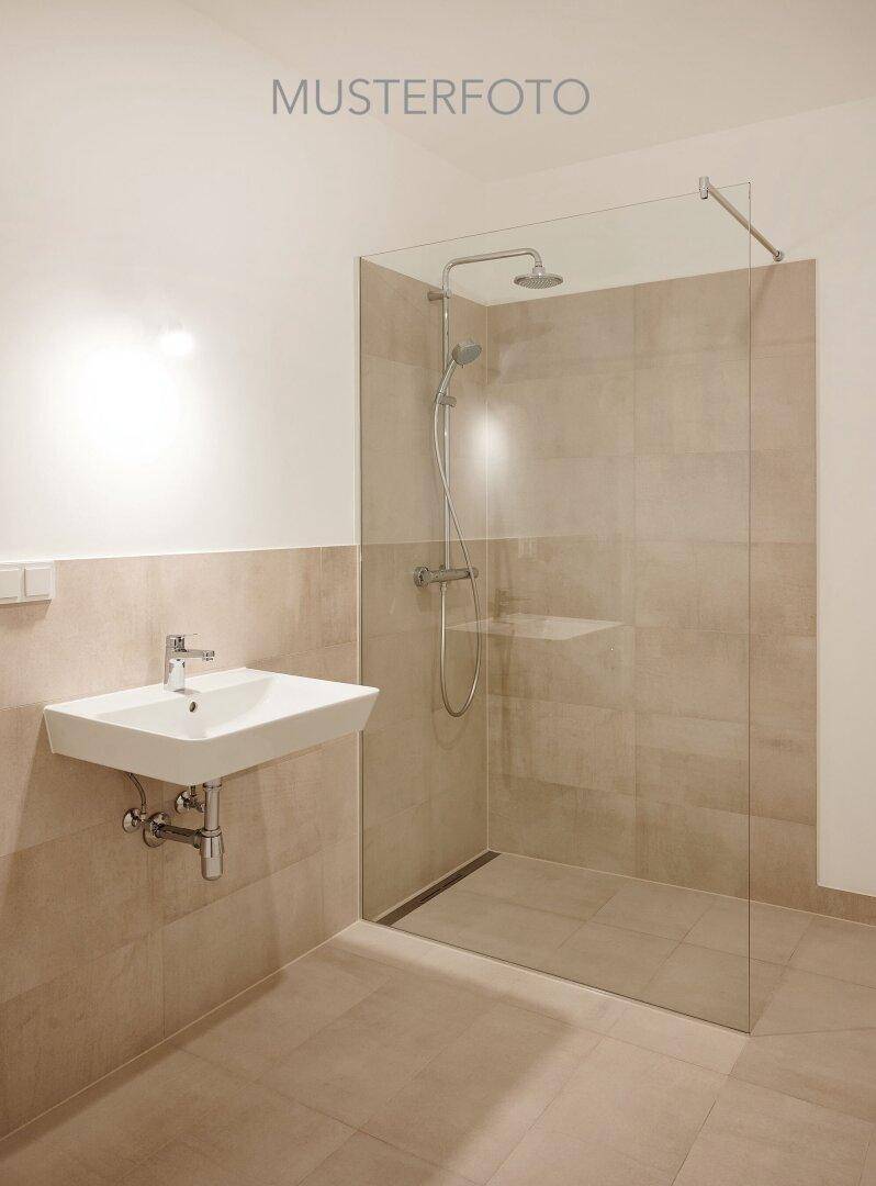 Modernes Badezimmer mit begehbarer Dusche, beigefarbenen Fliesen und Einzelwaschbecken.