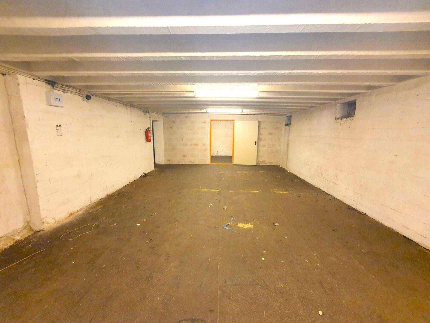Geräumiger Kellerraum mit weiß gestrichenen Wänden und sichtbaren Deckenbalken, bereit zur Nutzung.
