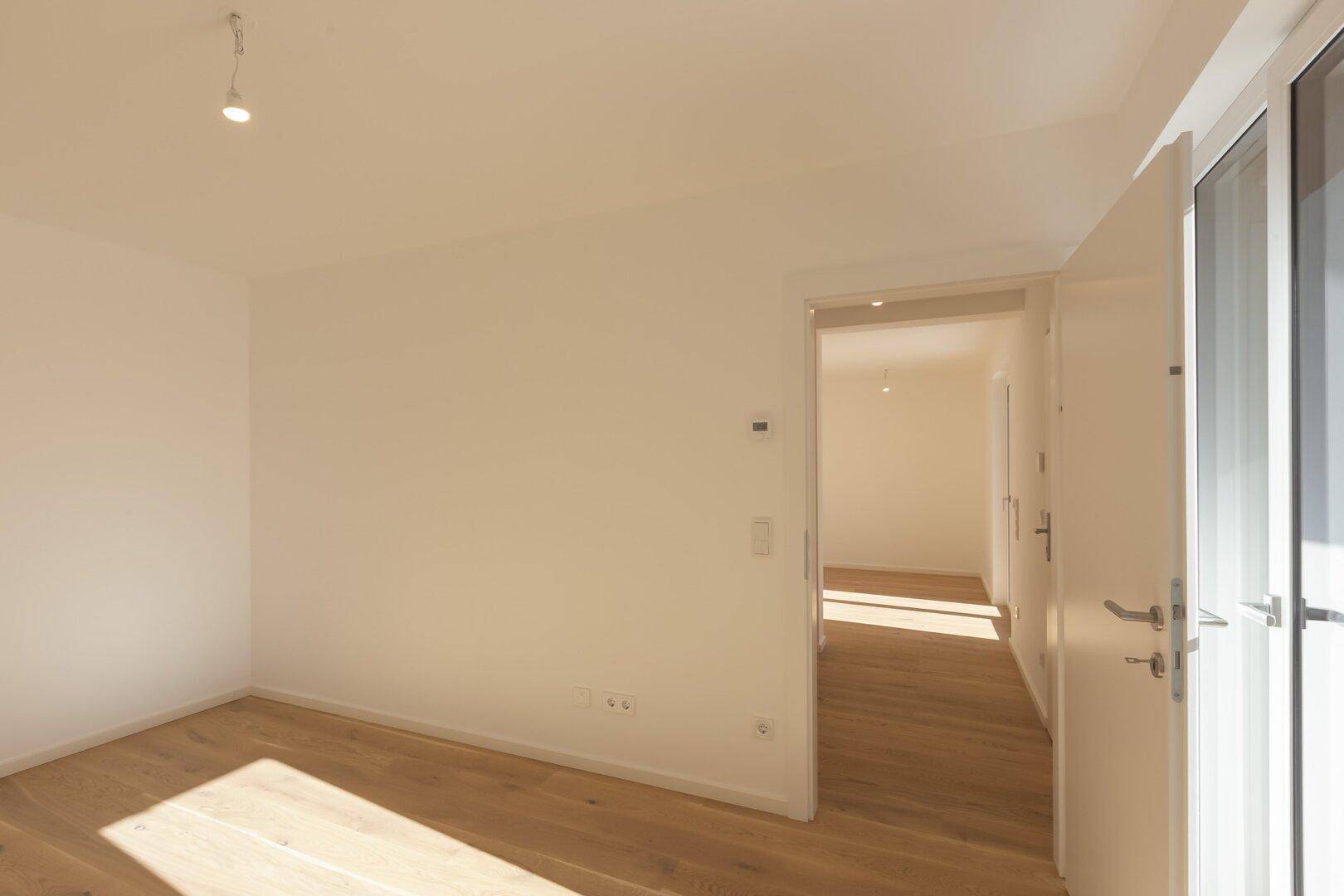 Leeres Schlafzimmer mit Holzboden und weiß gestrichenen Wänden, bereit zum Einrichten.