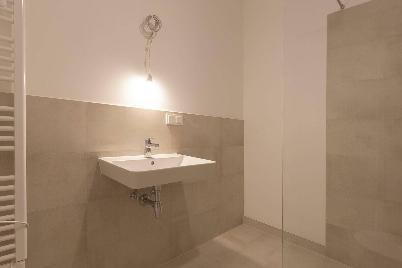 Modernes Badezimmer mit Einzelwaschbecken, beheiztem Handtuchhalter und beigefarbenen Fliesen.