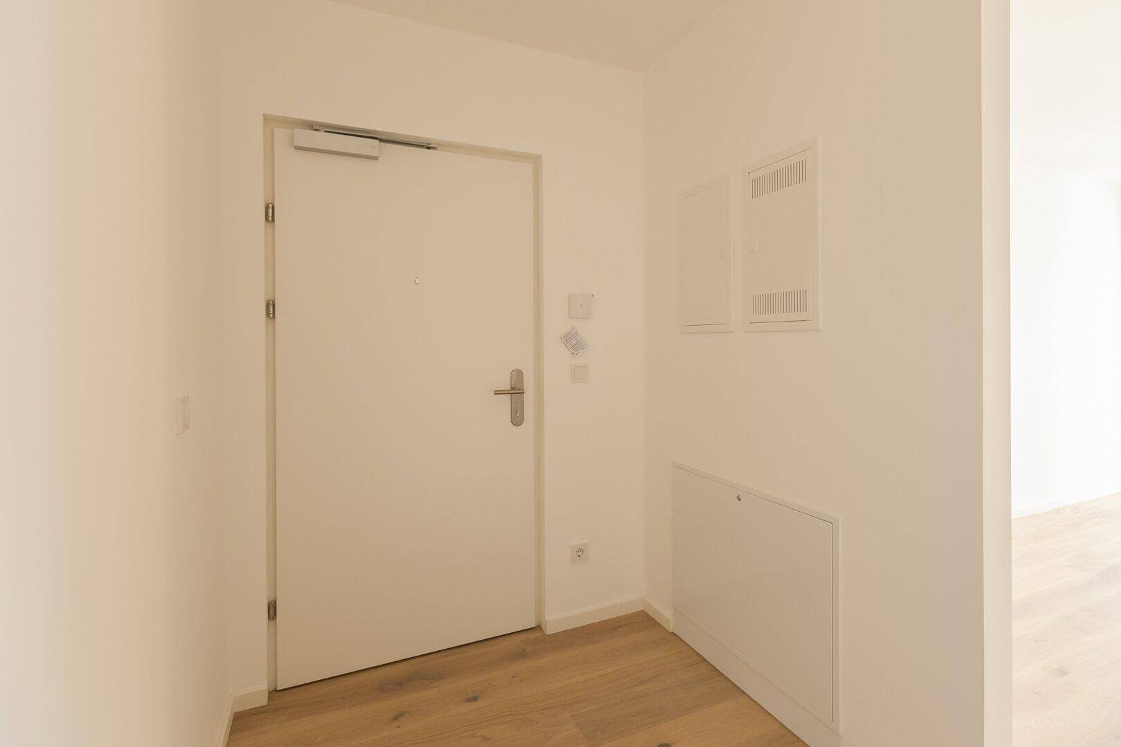 Eingangsbereich mit heller Tür und Holzboden, der einen freundlichen Empfang bietet.