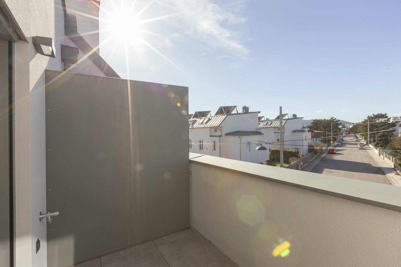 Heller Balkon mit Blick auf die Straße und umliegende Gebäude, ideal für sonnige Stunden.
