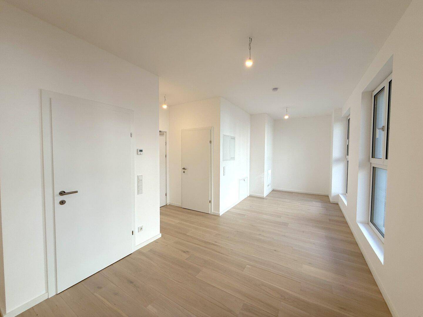 Geräumiger, heller Innenraum mit Holzboden und weißen Türen.