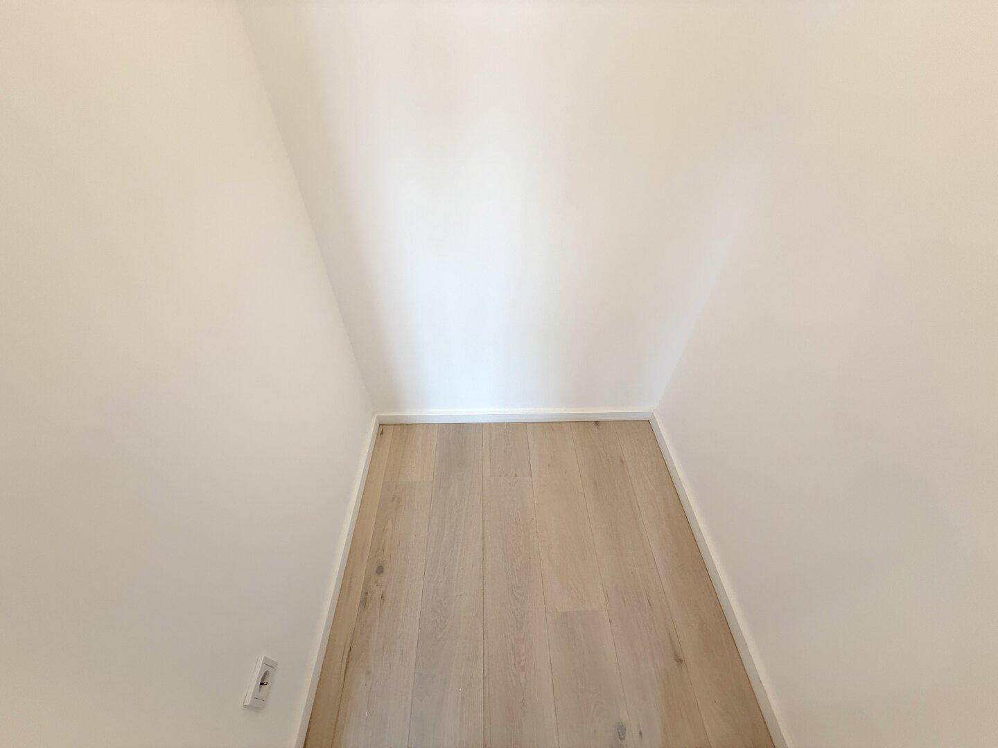 Schmaler, leerer Raum mit Holzboden, ideal als Abstellraum oder Garderobe.