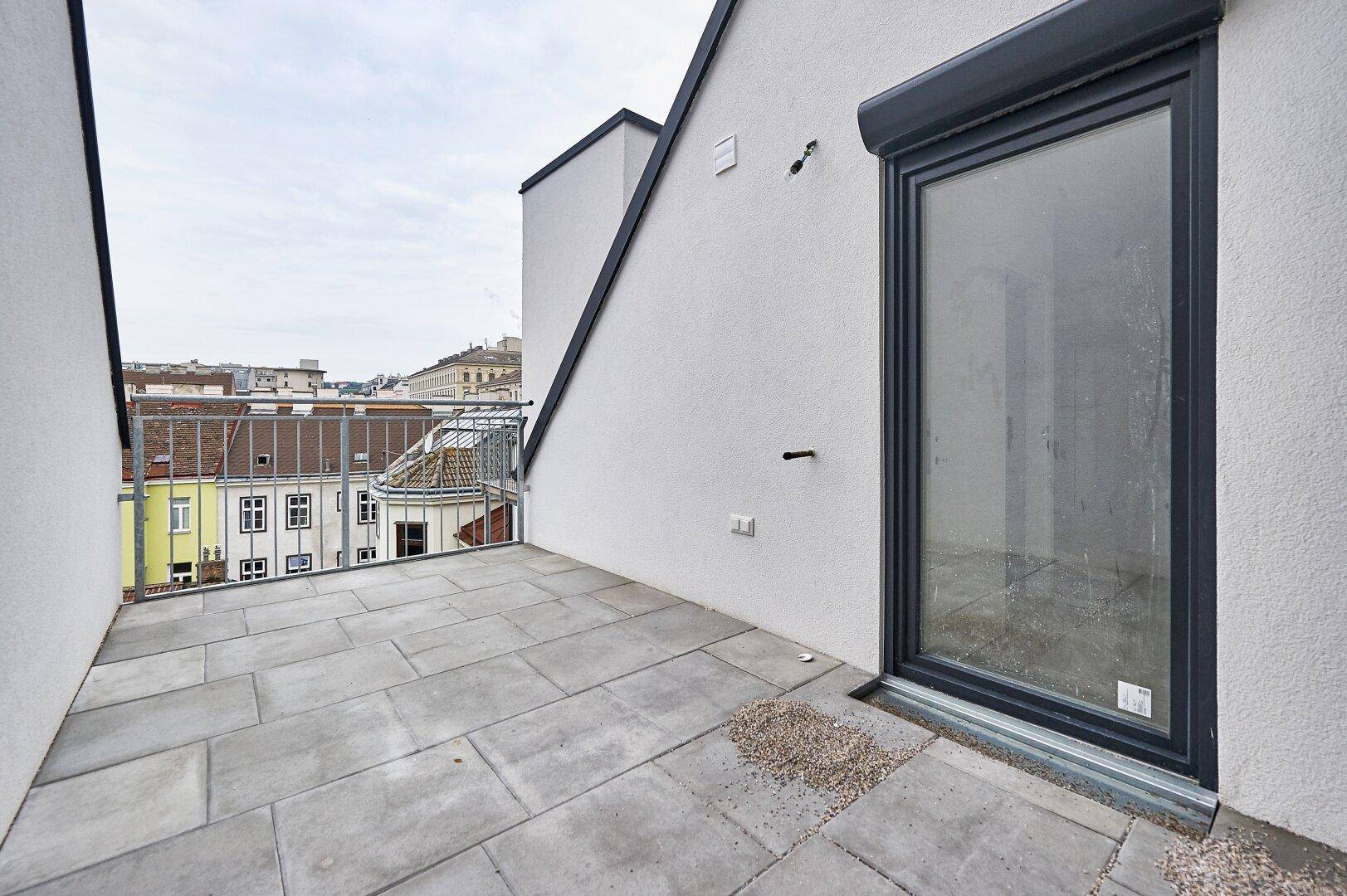 Geräumige Dachterrasse mit Steinplatten und Blick über die Dächer der Stadt, ideal zum Entspannen.