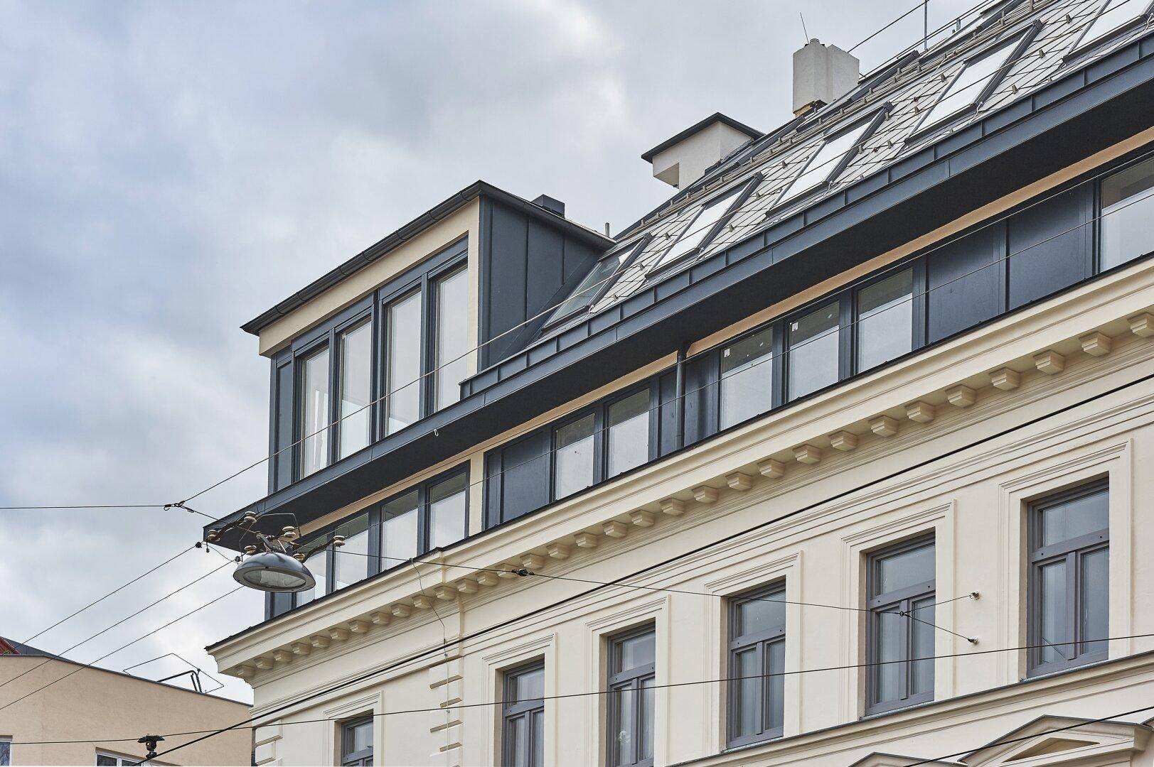 Detailansicht der modernen Dachaufstockung mit großen Fenstern und klassischer Fassadenarchitektur.