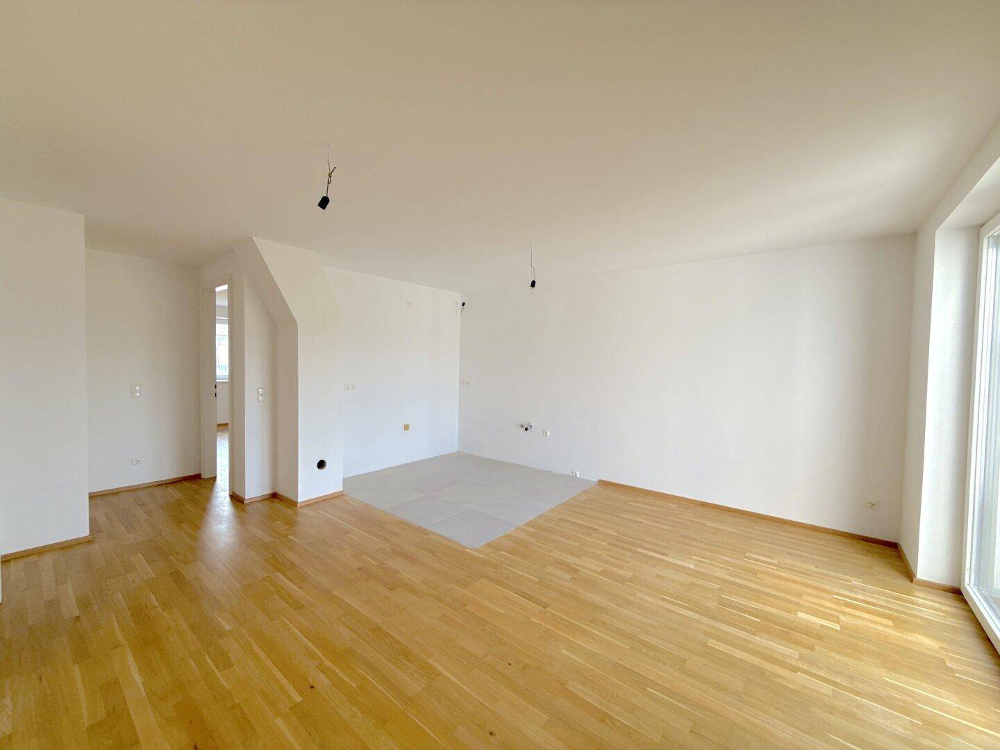 Heller Raum mit Parkettboden und einem gefliesten Bereich, der sich für eine offene Küche eignet.