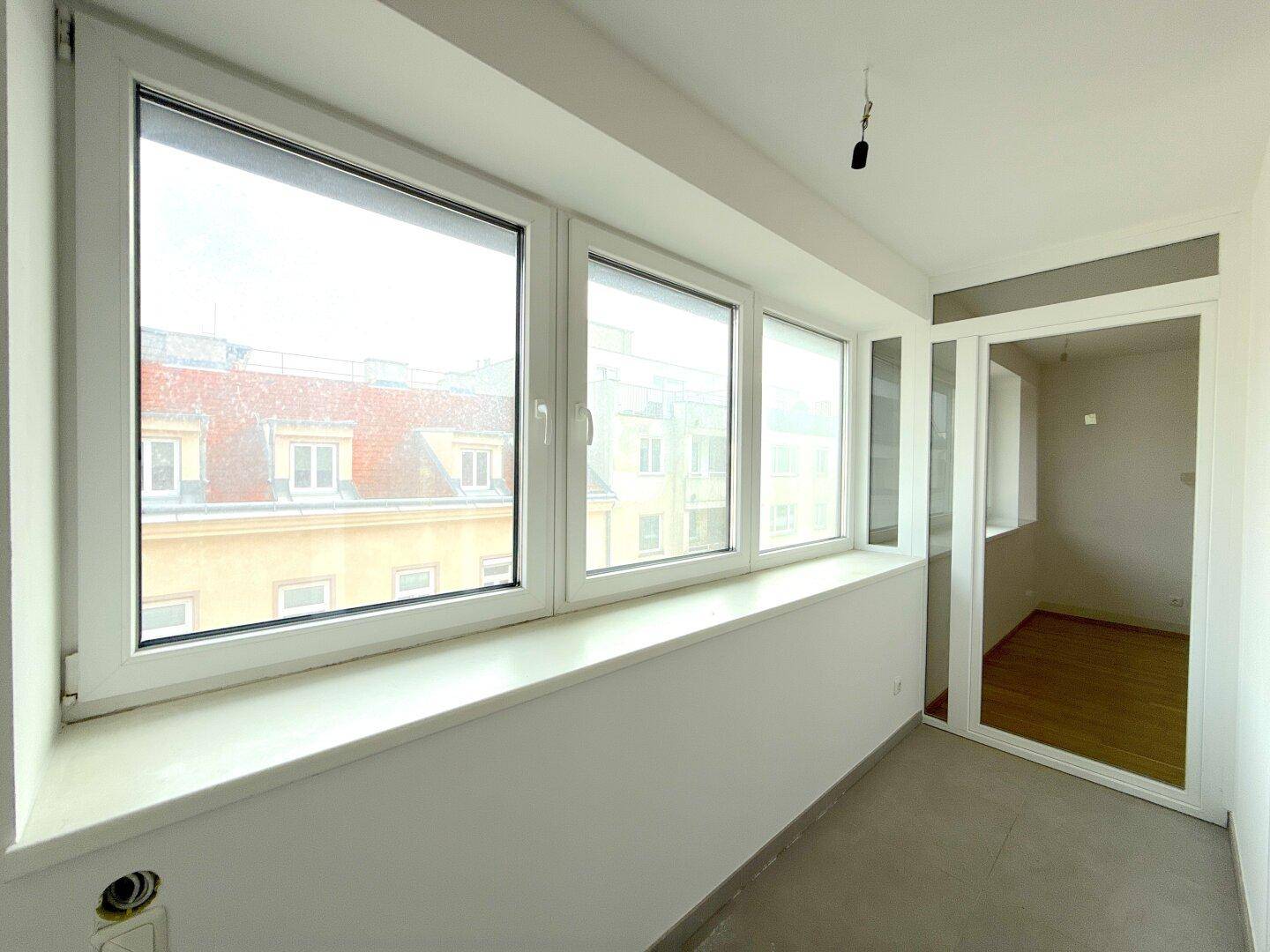 Verglaste Loggia mit weitem Fenster und Zugang zum Innenraum, ideal als sonniger Rückzugsort.