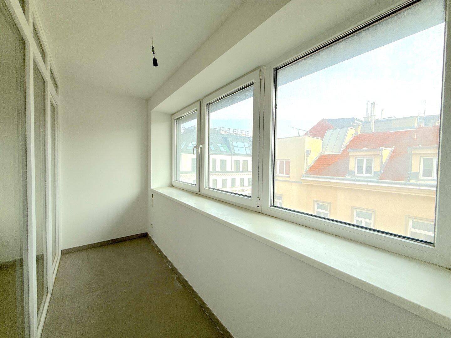 Helle, verglaste Loggia mit Blick auf die umliegenden Gebäude, bietet zusätzlichen Wohnraum.