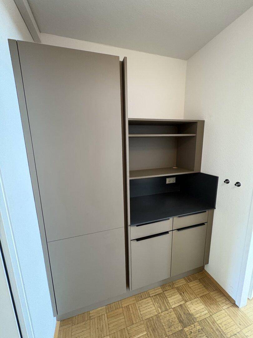 Moderne Küchenzeile mit grauen Schränken, Spüle und integrierten Geräten.