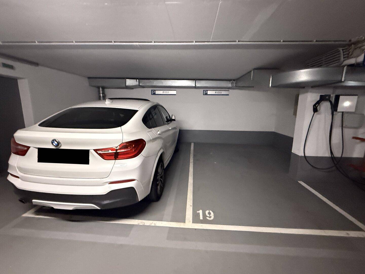 Moderner Tiefgaragenstellplatz mit Ladestation für Elektrofahrzeuge und geparktem weißen SUV.