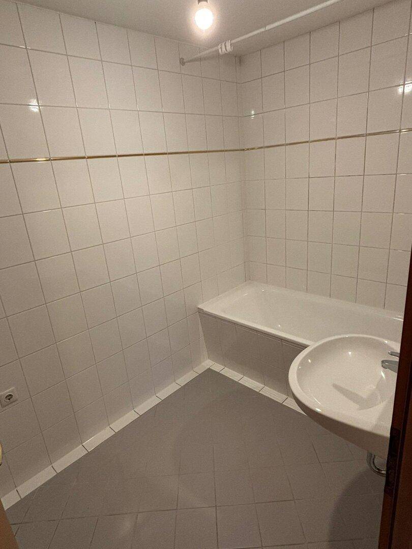 Modernes Badezimmer mit weißen Fliesen, Badewanne und Waschbecken, in gutem Zustand.