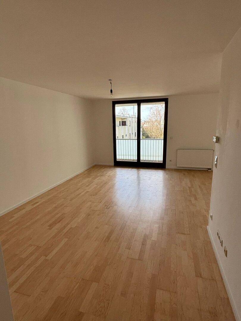 Heller Raum mit Parkettboden und Balkonzugang, bietet eine angenehme Atmosphäre und viel Licht.