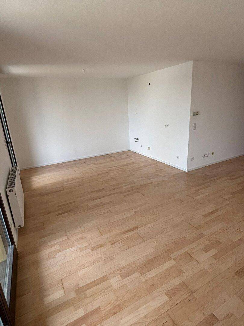 Heller Wohnbereich mit Parkettboden und weißen Wänden, bietet viel Gestaltungsfreiheit.