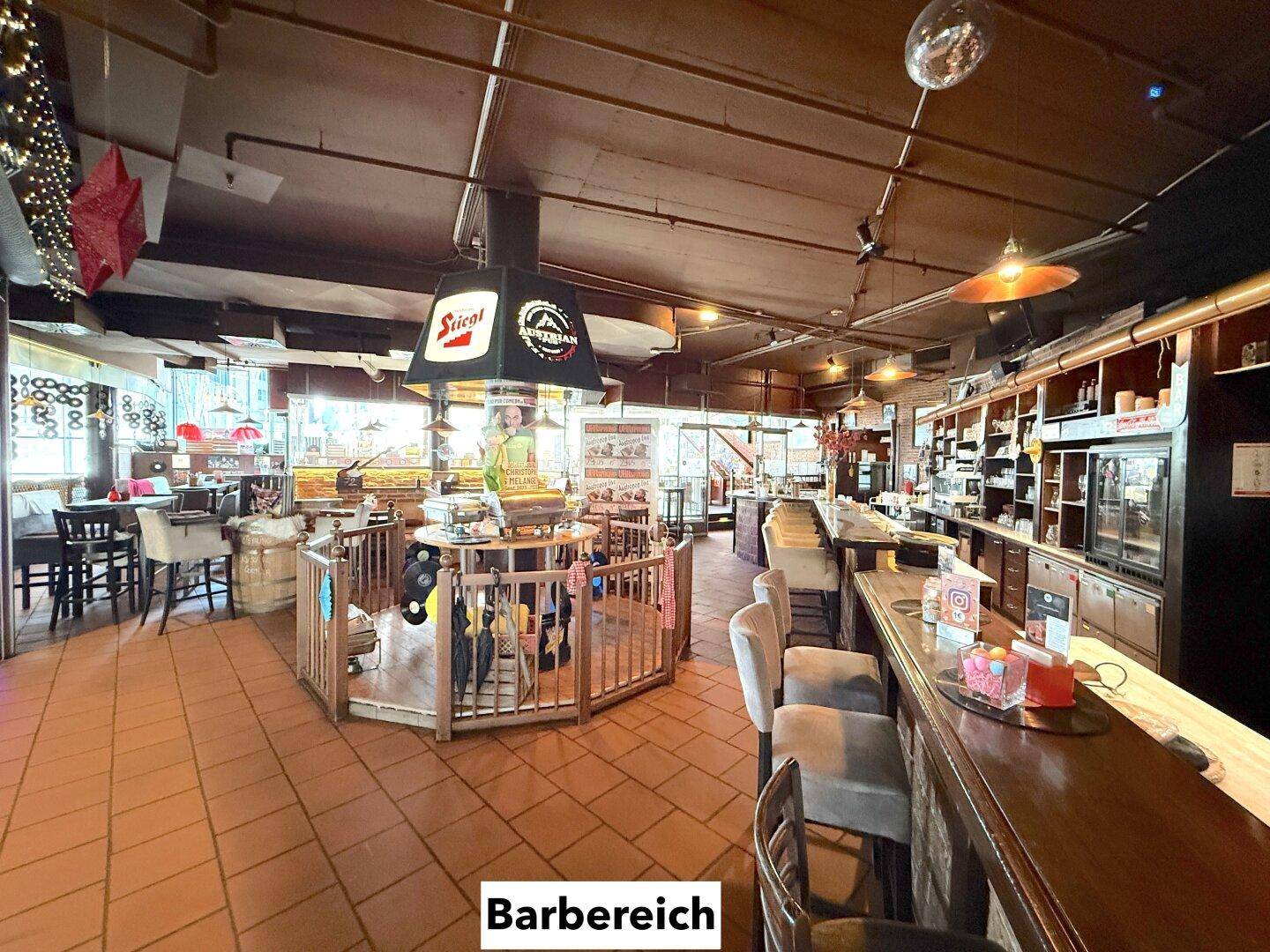 Bar-Bereich mit Theke, Barhockern und einem zentralen runden Tresen, umgeben von Terrakotta-Fliesen.