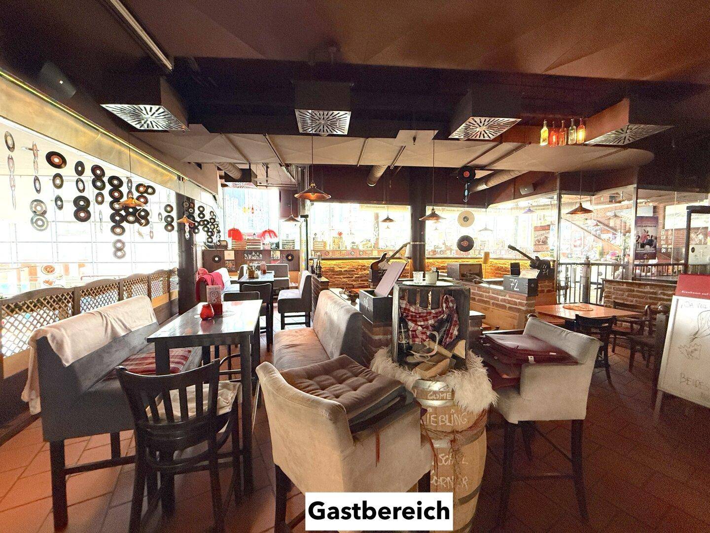 Gemütlicher Gastbereich mit verschiedenen Sitzgelegenheiten, Holztischen und dekorativen Elementen an der Decke.