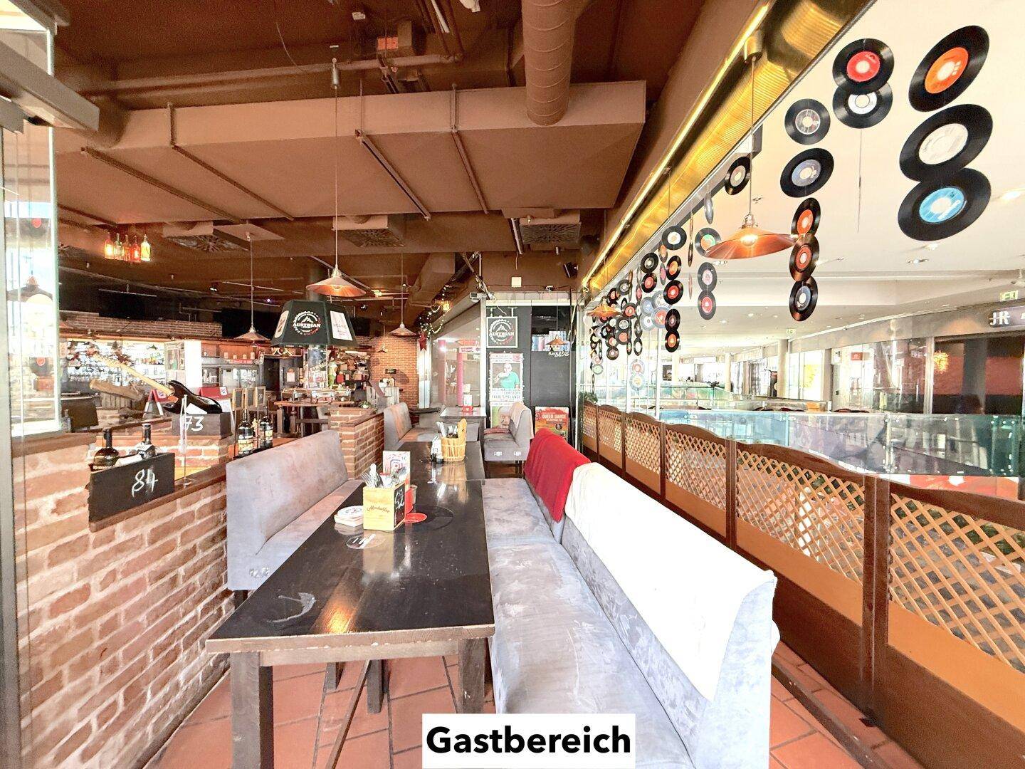 Gemütlicher Gastbereich mit gepolsterten Bänken, Holztischen und dekorativen Elementen an den Wänden.