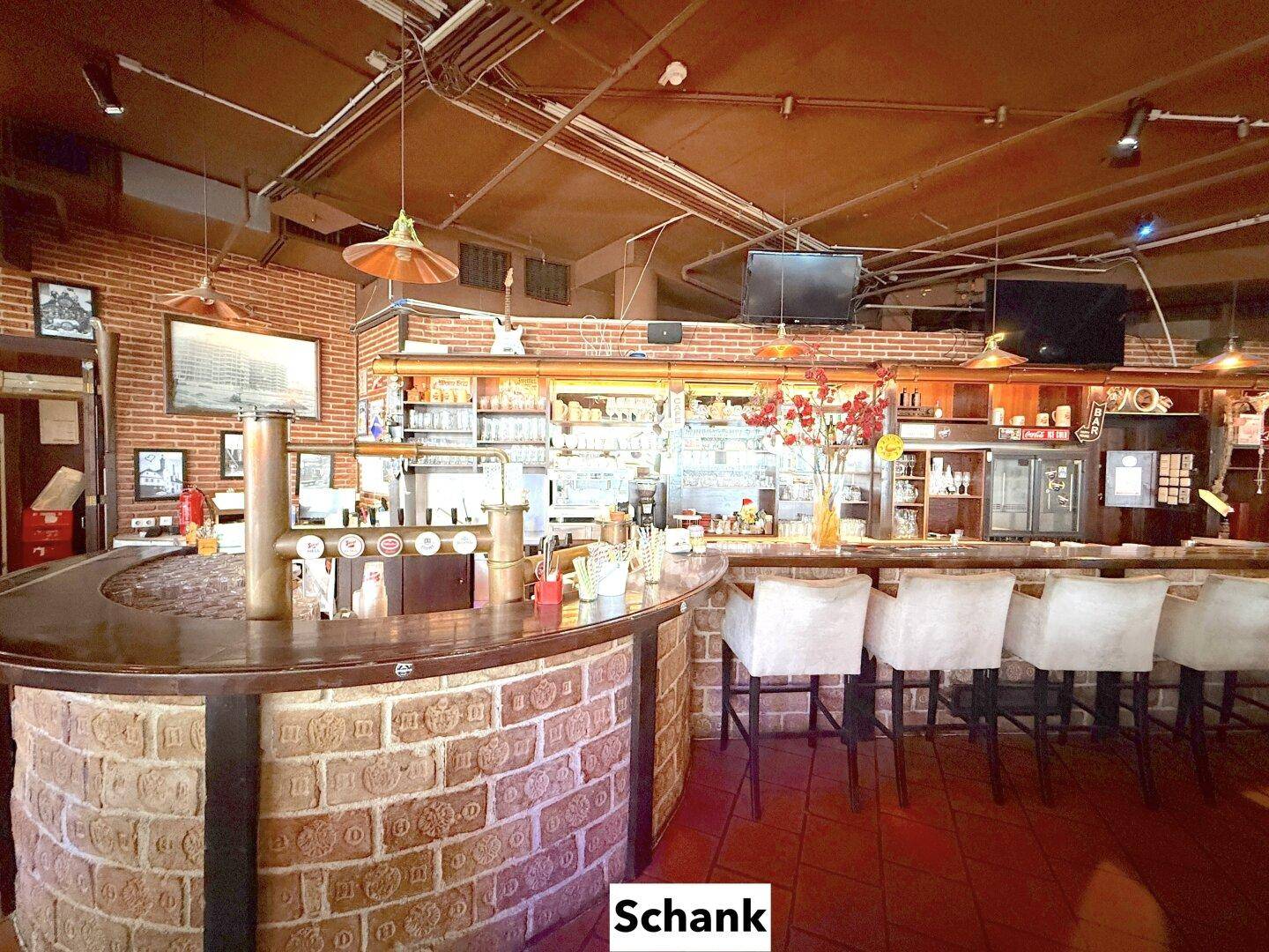 Detailansicht der Bar mit Zapfanlage, Flaschenregalen und gemauertem Tresen, ergänzt durch bequeme Barhocker.