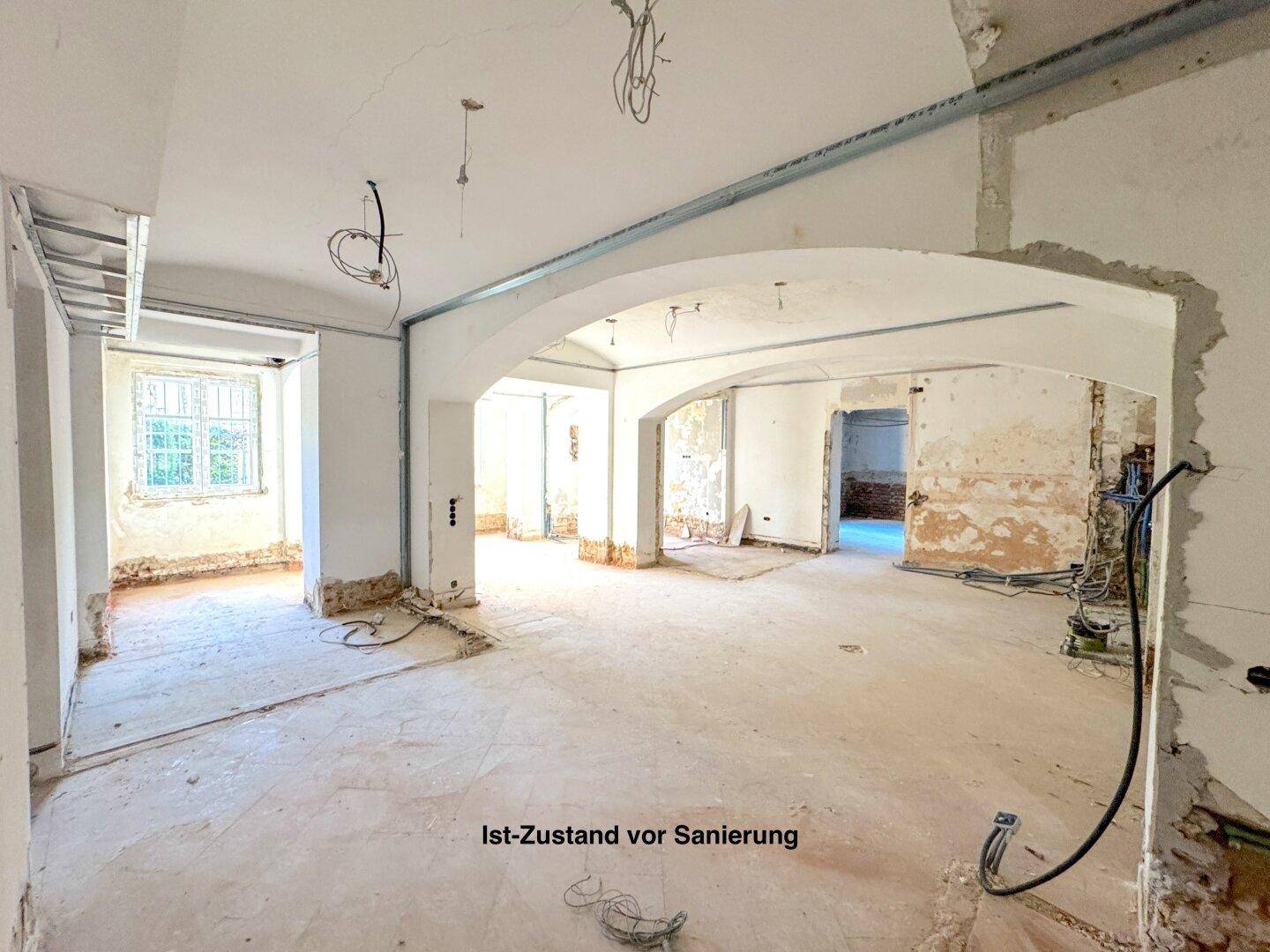 Großer offener Raum im Rohzustand mit Bögen und vorbereiteten Installationen für die Sanierung.