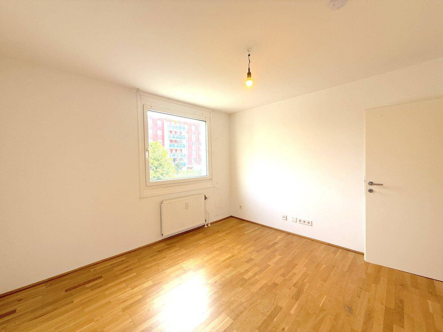 Ruhiges Schlafzimmer mit Holzboden und einem Fenster, das einen Blick nach draußen bietet.