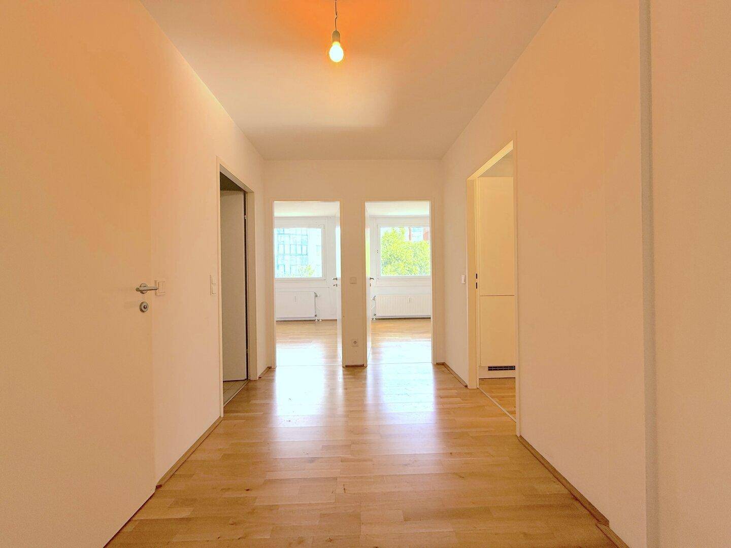 Heller Flur mit Parkettboden, der zu verschiedenen Zimmern der Wohnung führt.