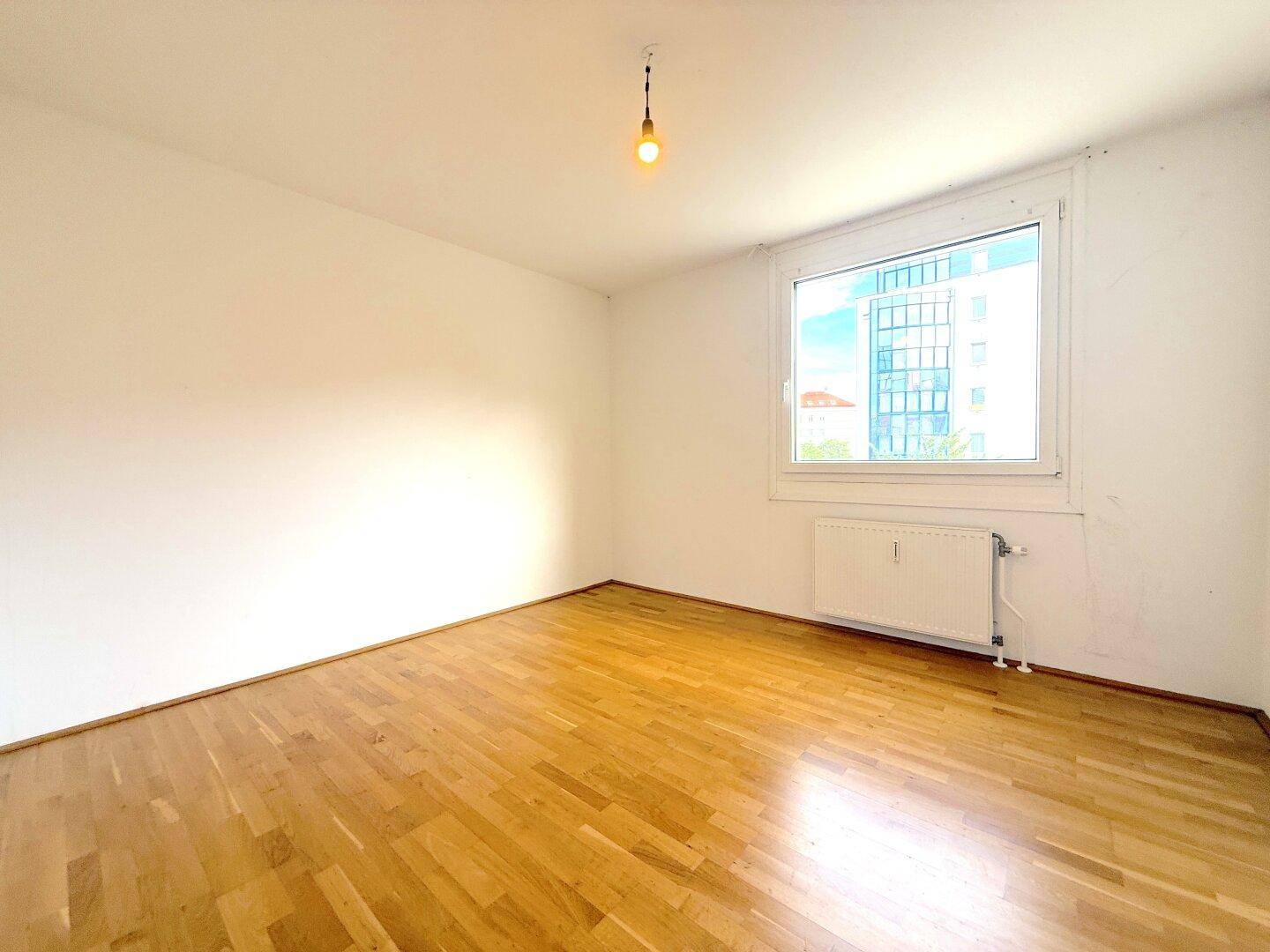 Helles Zimmer mit Holzboden und einem Fenster, das einen weiten Blick auf die Umgebung bietet.
