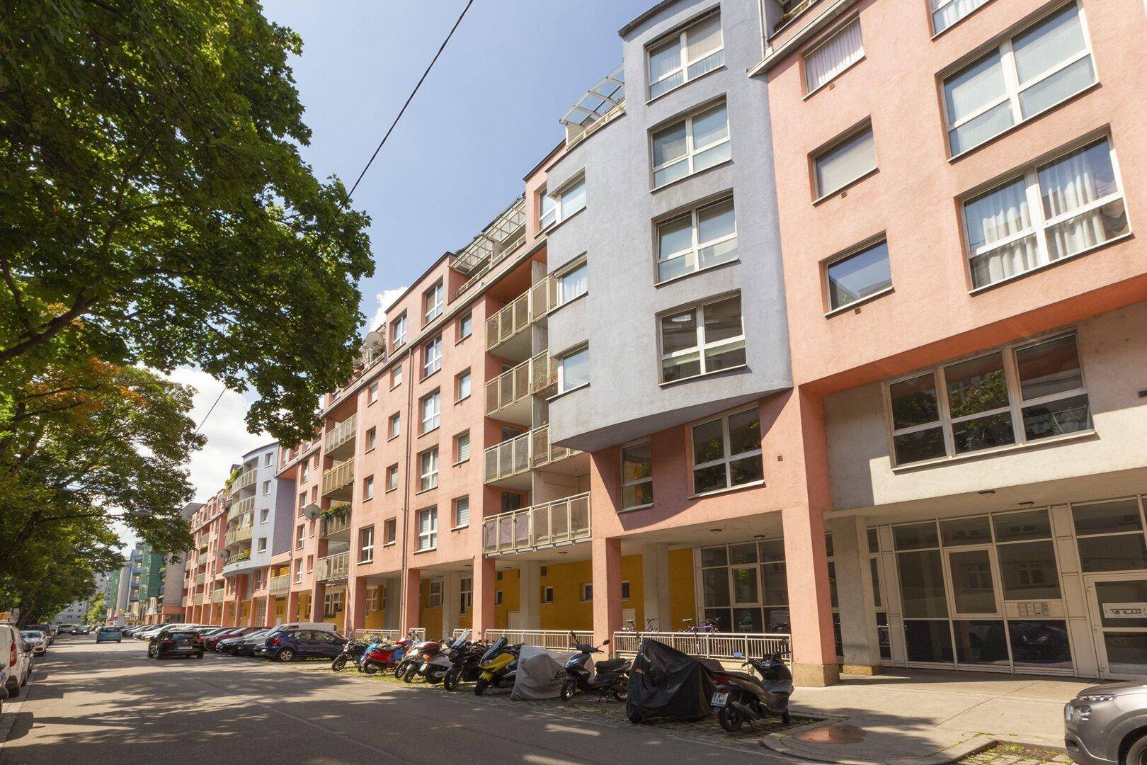 Moderne Wohngebäude entlang einer Straße mit Balkonen und geparkten Fahrzeugen.