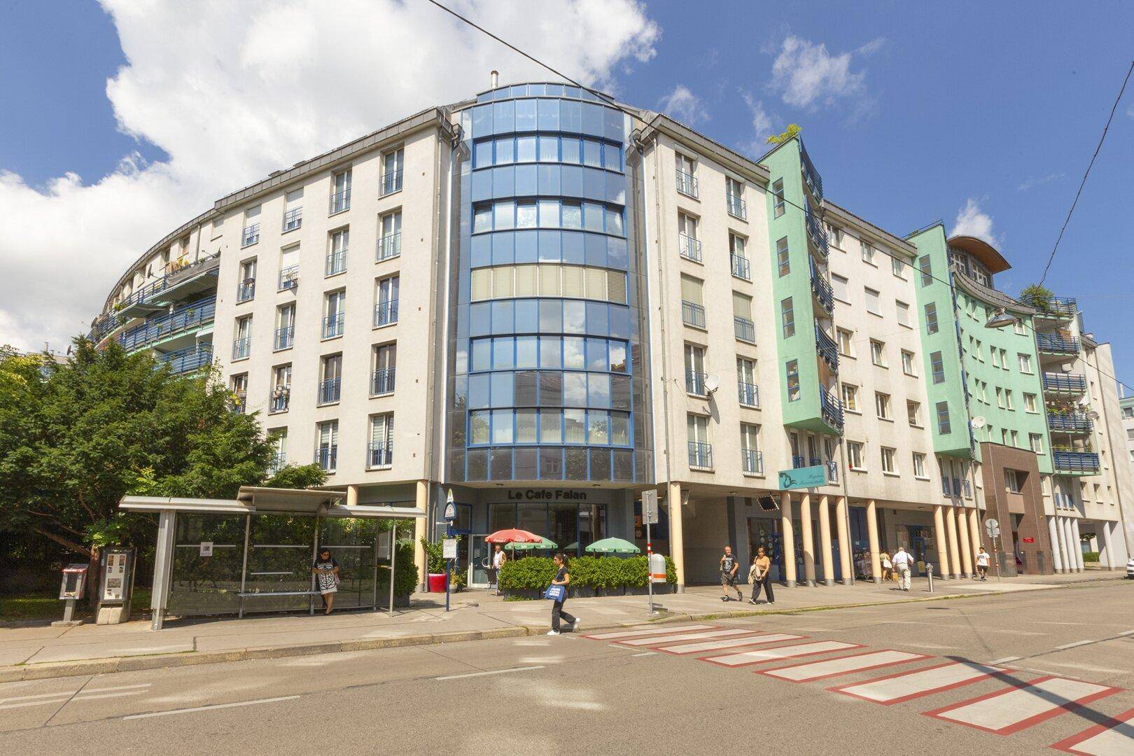 Großes, modernes Wohngebäude mit geschwungener Glasfassade und Geschäften im Erdgeschoss.