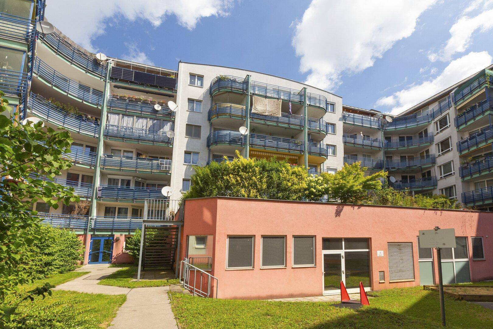 Wohngebäude mit mehreren Balkonen und begrüntem Dachbereich im Innenhof der Anlage.