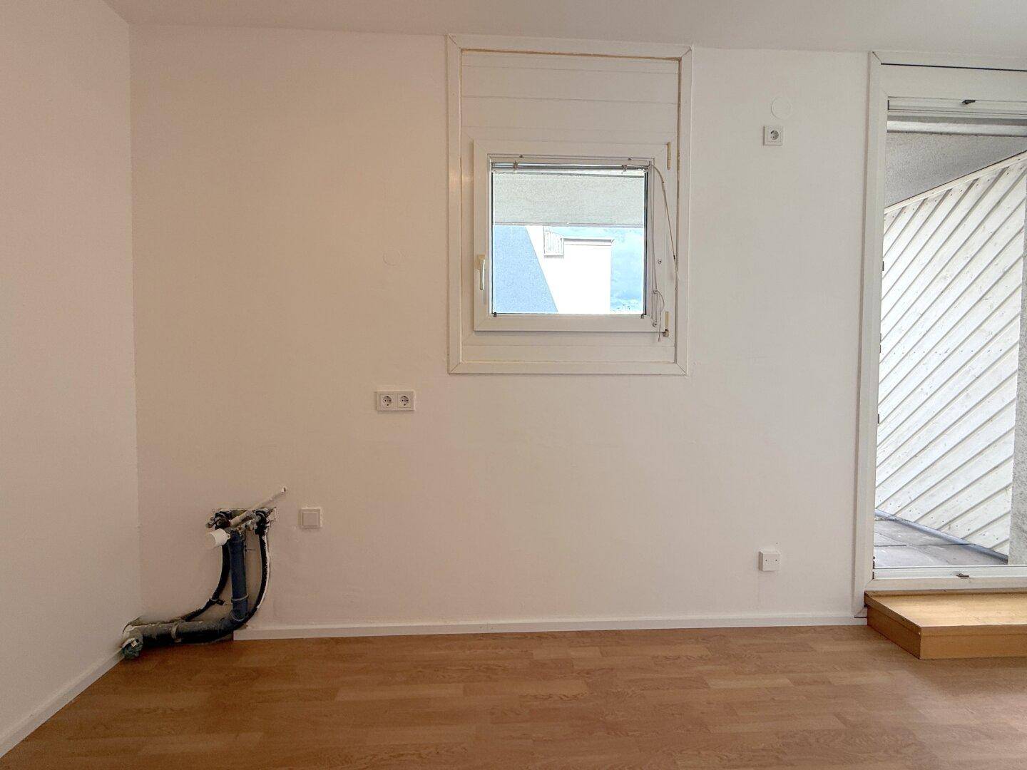Wandbereich mit Wasseranschlüssen und Fenster, bereit für die Kücheninstallation.