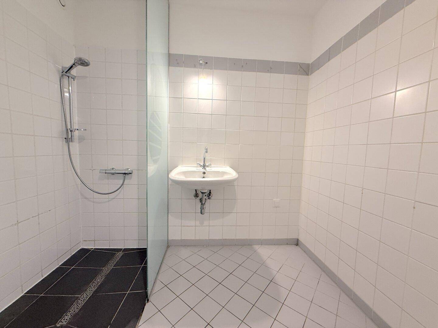 Modernes Badezimmer mit Duschbereich, Fliesenboden und einem einzelnen Waschbecken.
