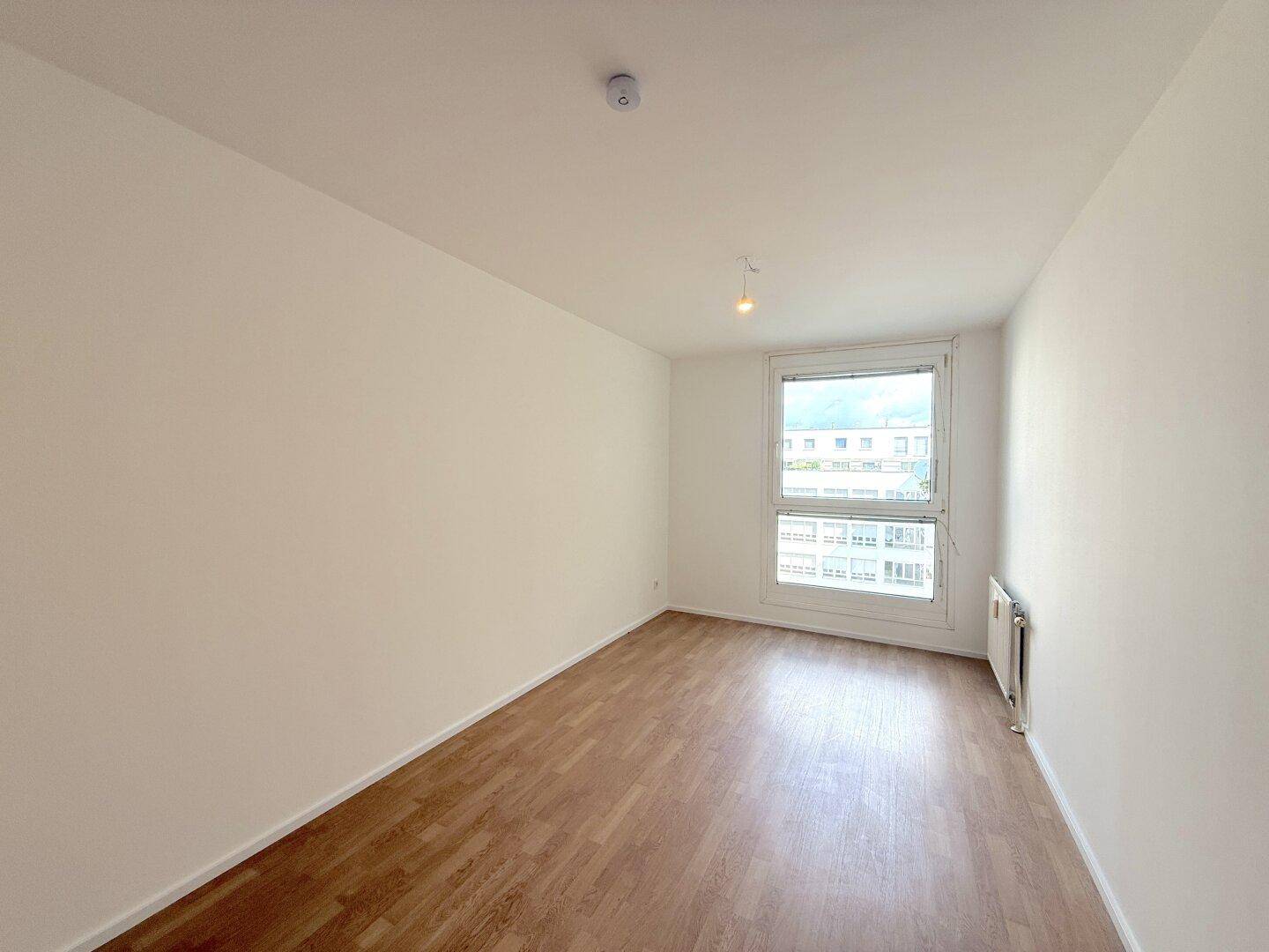 Geräumiges Zimmer mit hellem Laminatboden und großem Fenster für natürliche Belichtung.