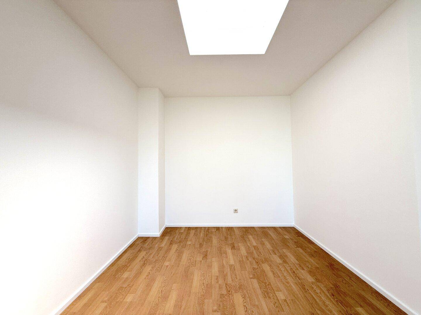 Kleiner, heller Raum mit Laminatboden und einer Deckenleuchte, vielseitig nutzbar.