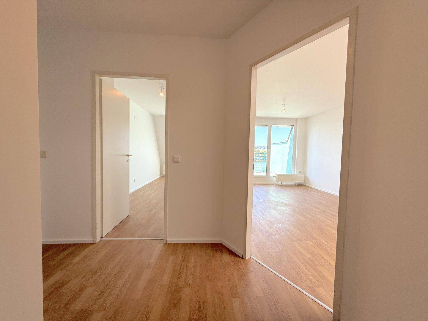 Heller Flur mit Laminatboden, der zu weiteren Zimmern der Wohnung führt.