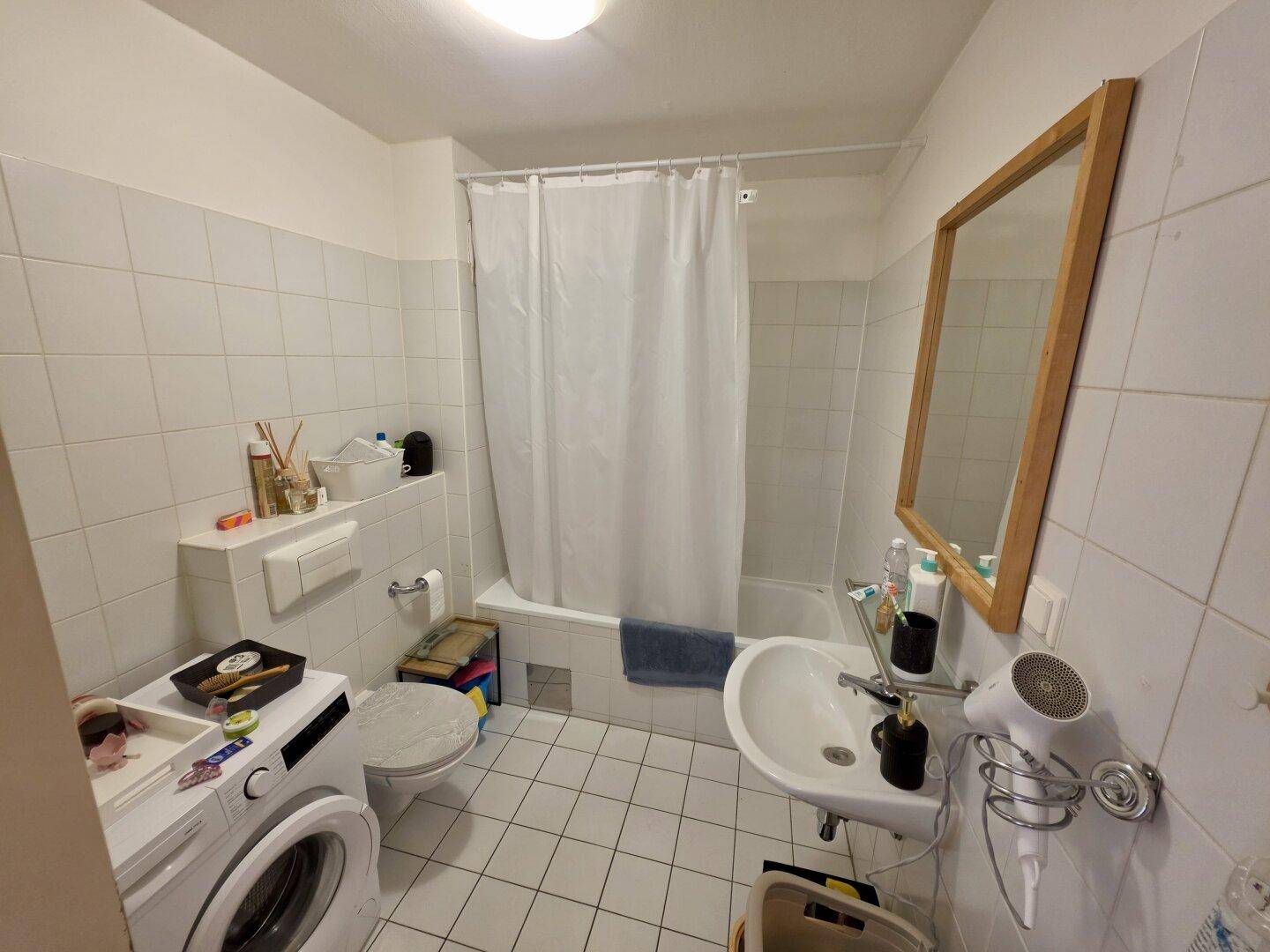 Funktionales Badezimmer mit Badewanne, Waschbecken, Toilette und Waschmaschine.