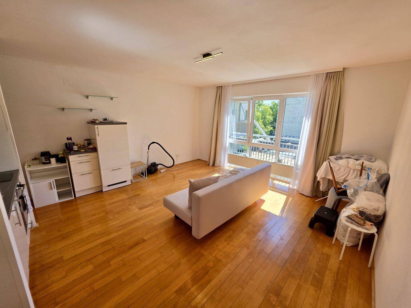 Geräumiger Wohnbereich mit Sofa und großem Fenster, das den Raum mit Tageslicht füllt.