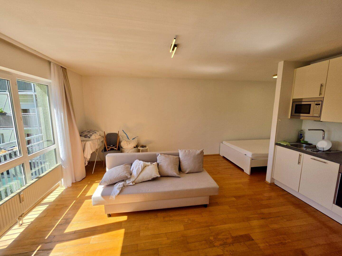 Geräumiges Studio-Apartment mit integrierter Küchenzeile, Schlafbereich und viel Tageslicht.