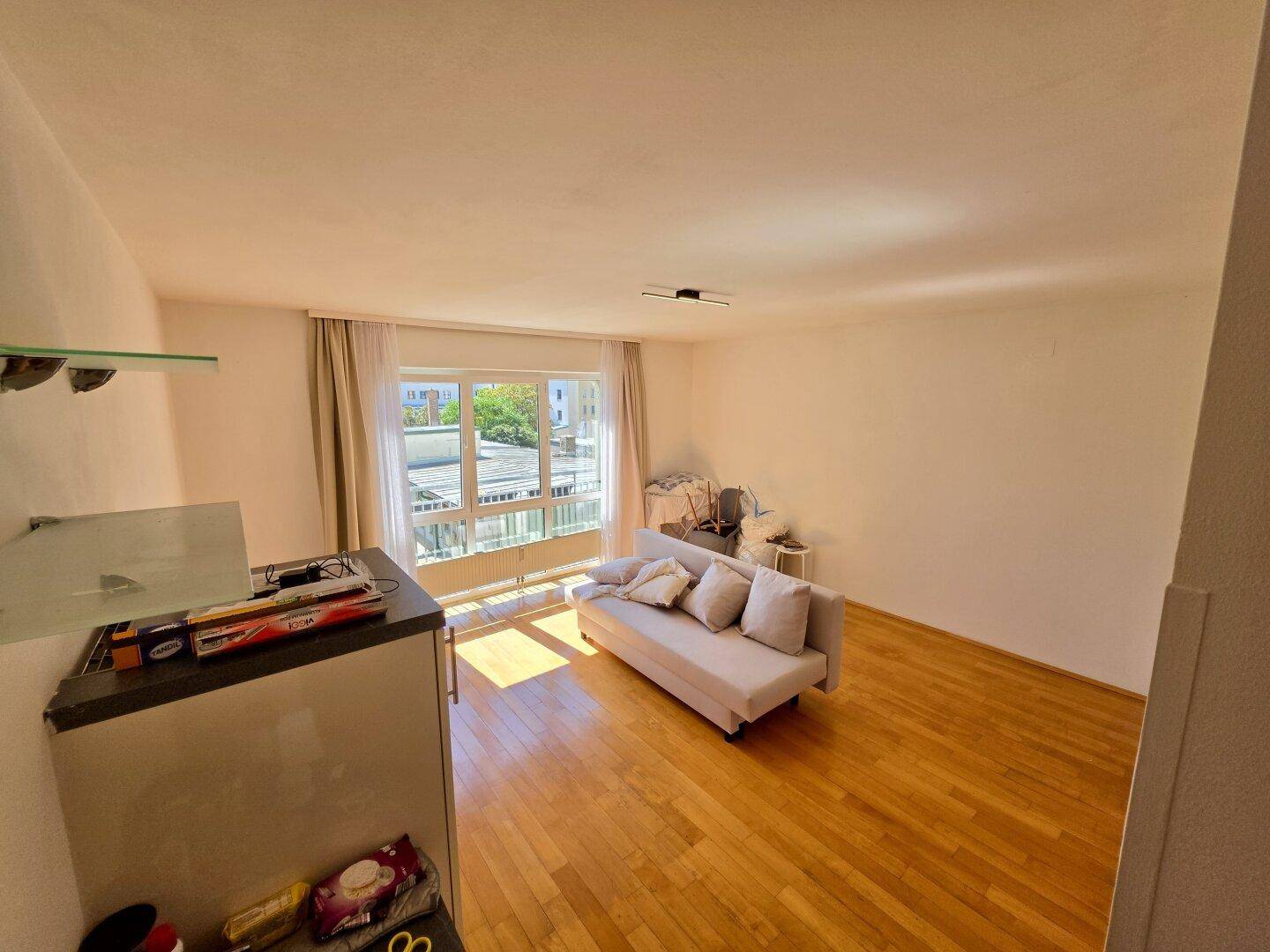 Heller Wohnbereich mit Sofa und großem Fenster, das einen weiten Blick nach draußen bietet.