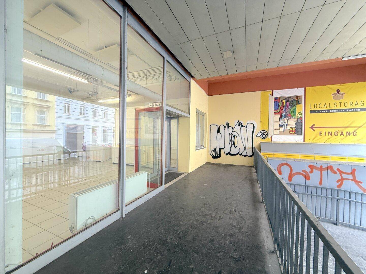 Außenansicht des Gebäudes mit Rampe, großen Glasfronten und Graffiti an der Fassade.