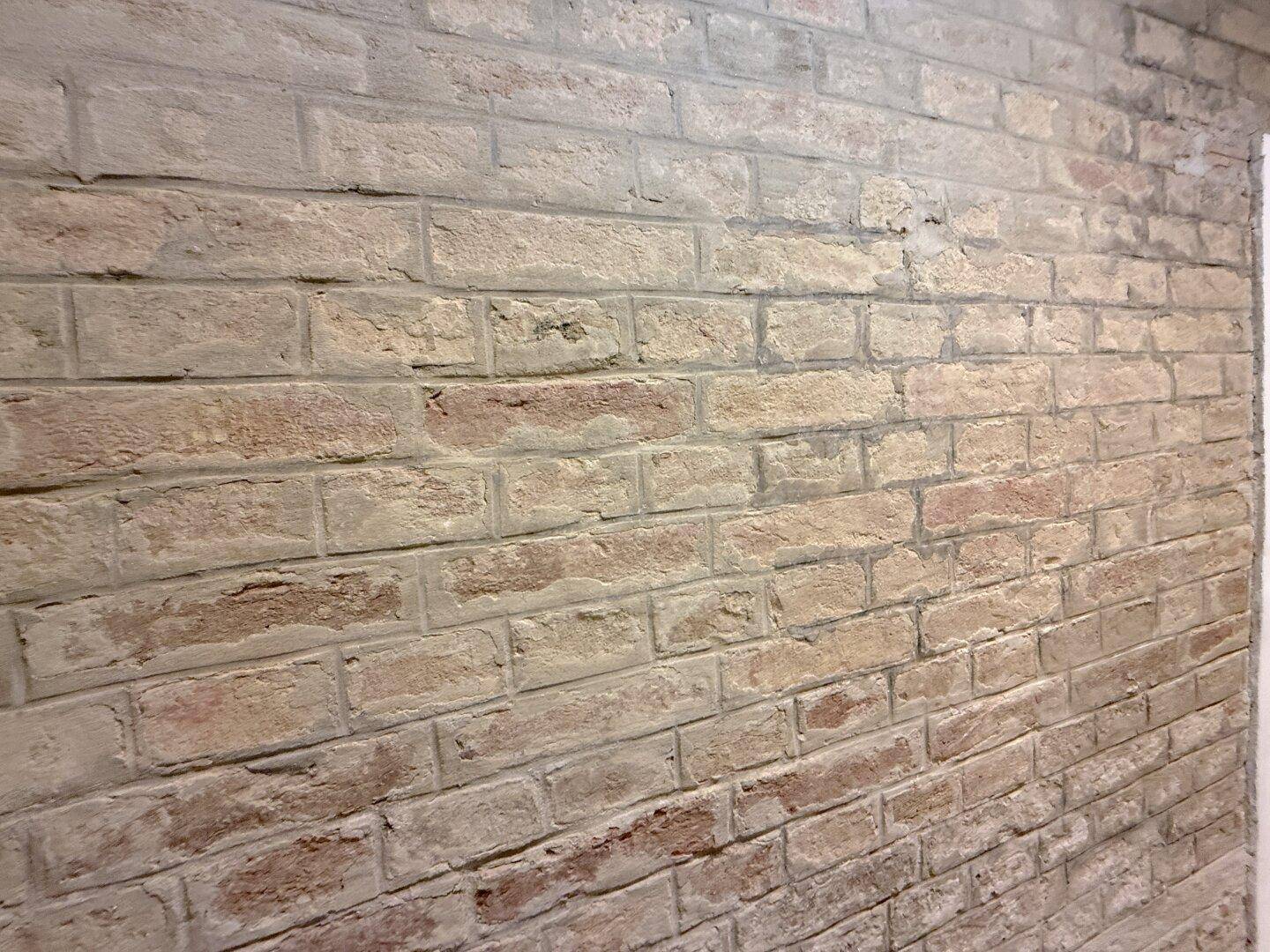 Nahaufnahme einer Wand mit freigelegten Ziegeln, die eine rustikale Textur zeigt.